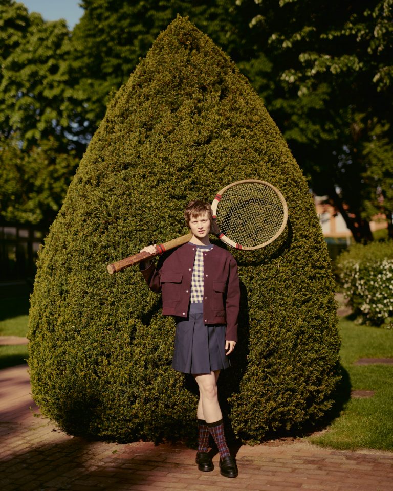 Femme devant un buisson avec une grosse raquette de tennis